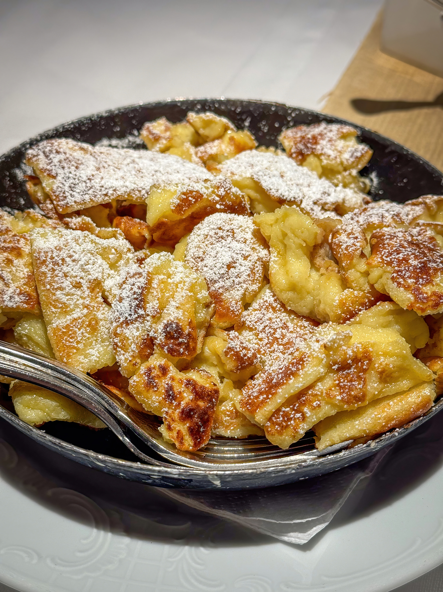 Frisch gebratener Kaiserschmarrn in einer Pfanne mit Puderzucker.