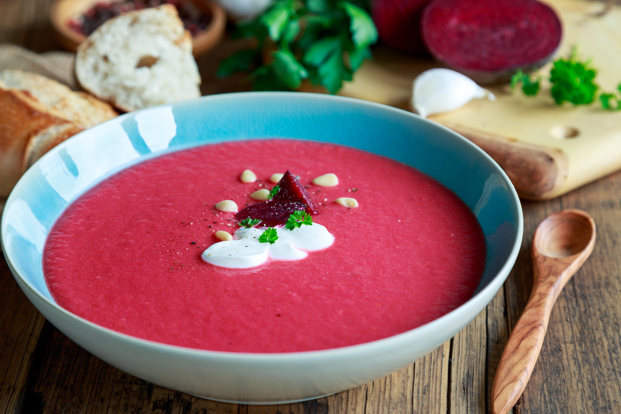 Eine breite Schale mit pinker Rote-Bete-Suppe, darauf Joghurt, Pinienkerne und Kräuter.