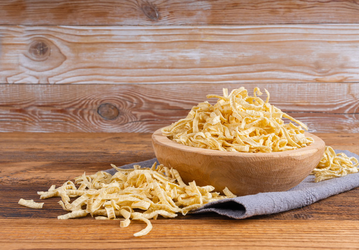 Holzschale mit getrockneten selbstgemachten Spätzle auf rustikalem Holztisch.