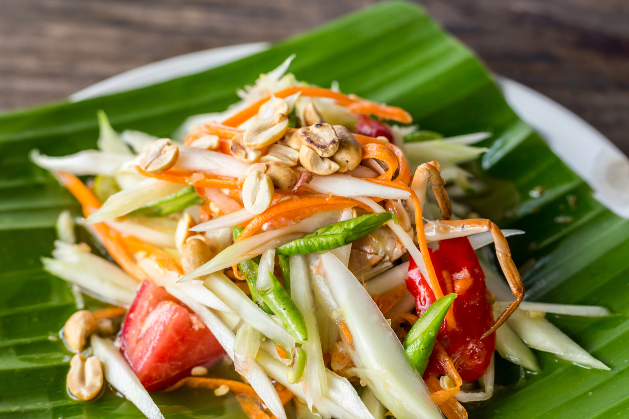 Som Tam Thai ist auf einem Bananenblatt angerichtet und mit Erdnüssen und Gemüse garniert.
